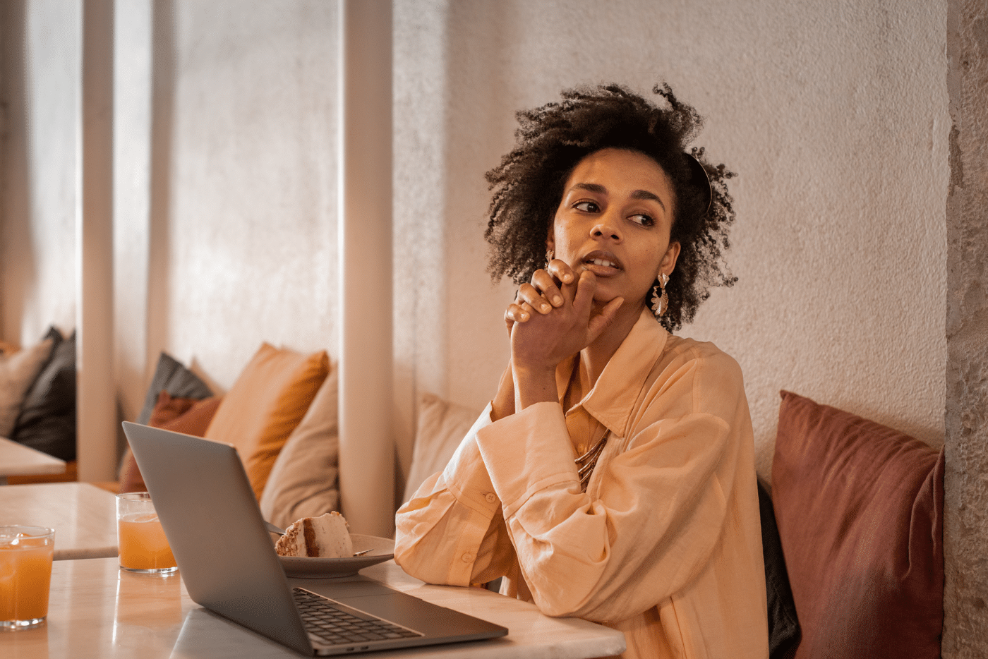 Remote working candid portrait of African beautiful pensive young woman with laptop in cafeteria.